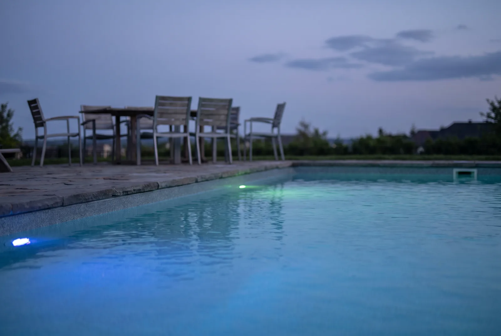 Éclairage immergé allumé dans une piscine creusée à la tombée du jour